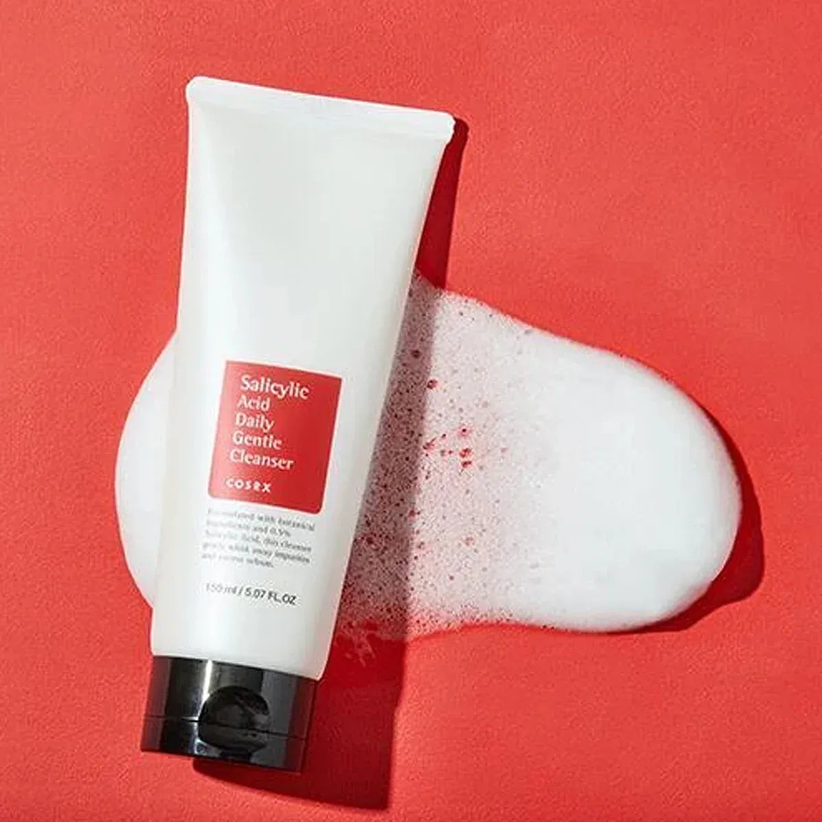 Tube of COERX Salicylic Acid Daily Gentle Cleanser with foam on a red background