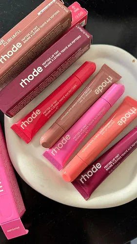 Collection of Rhode lip products on a white plate with a dark background